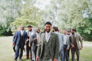 Groomsmen in suits walking through a lush garden setting.