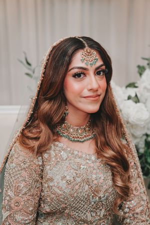 Close-up of bride wearing intricate traditional South Asian bridal jewelry and makeup.