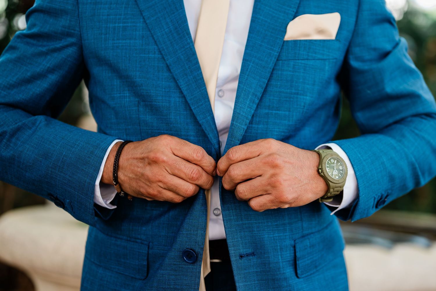Groom buttoning his blue suit before the wedding in Geneva, Switzerland
