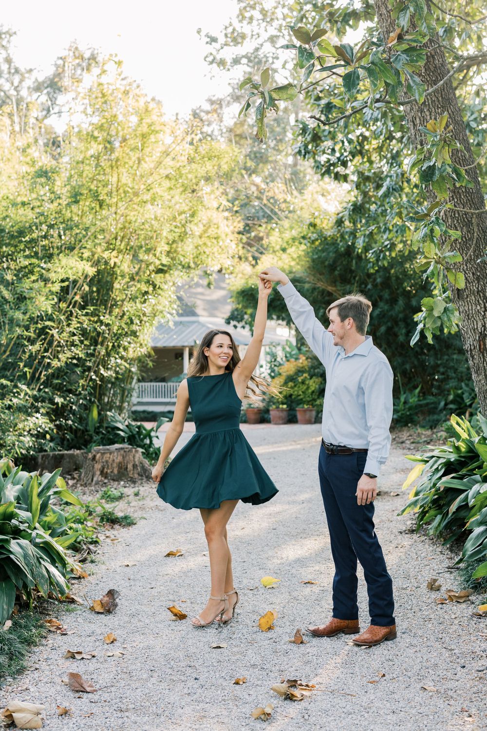 Couple dancing playfully on garden path surrounded by lush greenery.