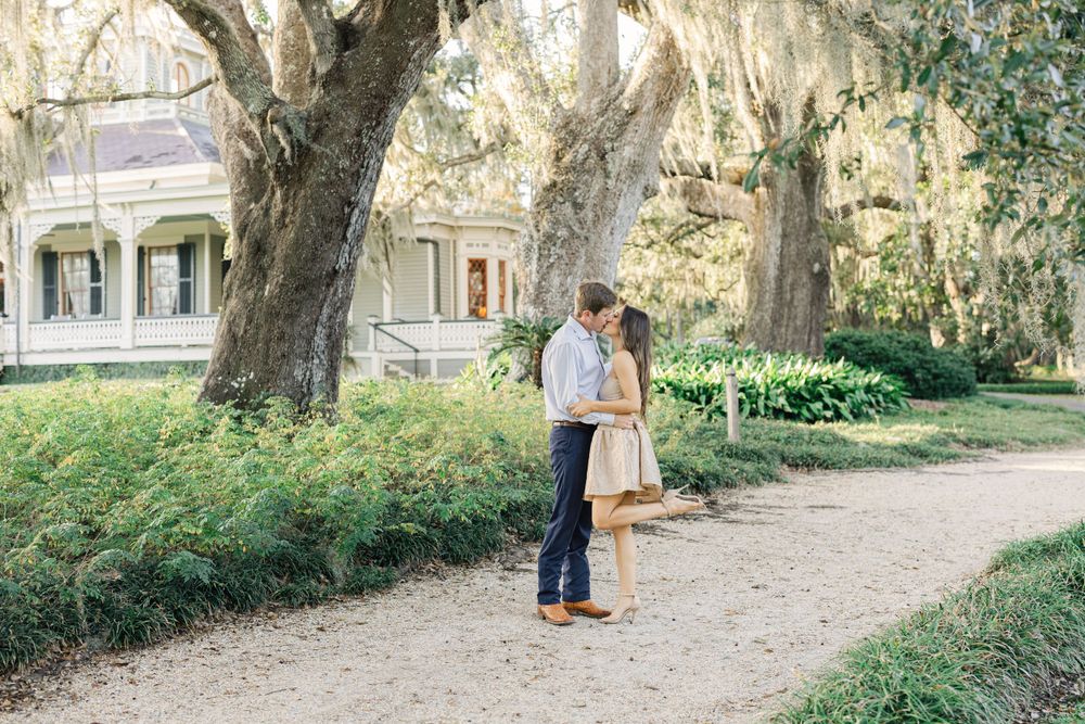 Couple embracing on garden path with historic mansion and Spanish moss in background.