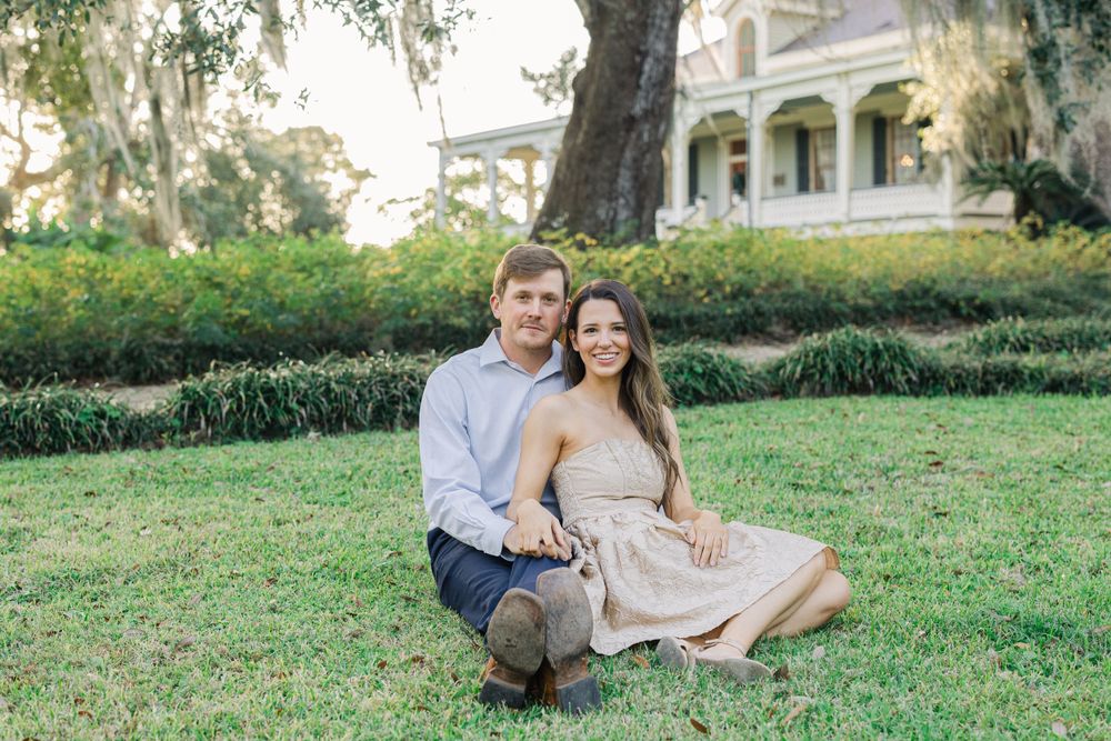 Couple sitting together on lawn in front of Southern plantation style home.