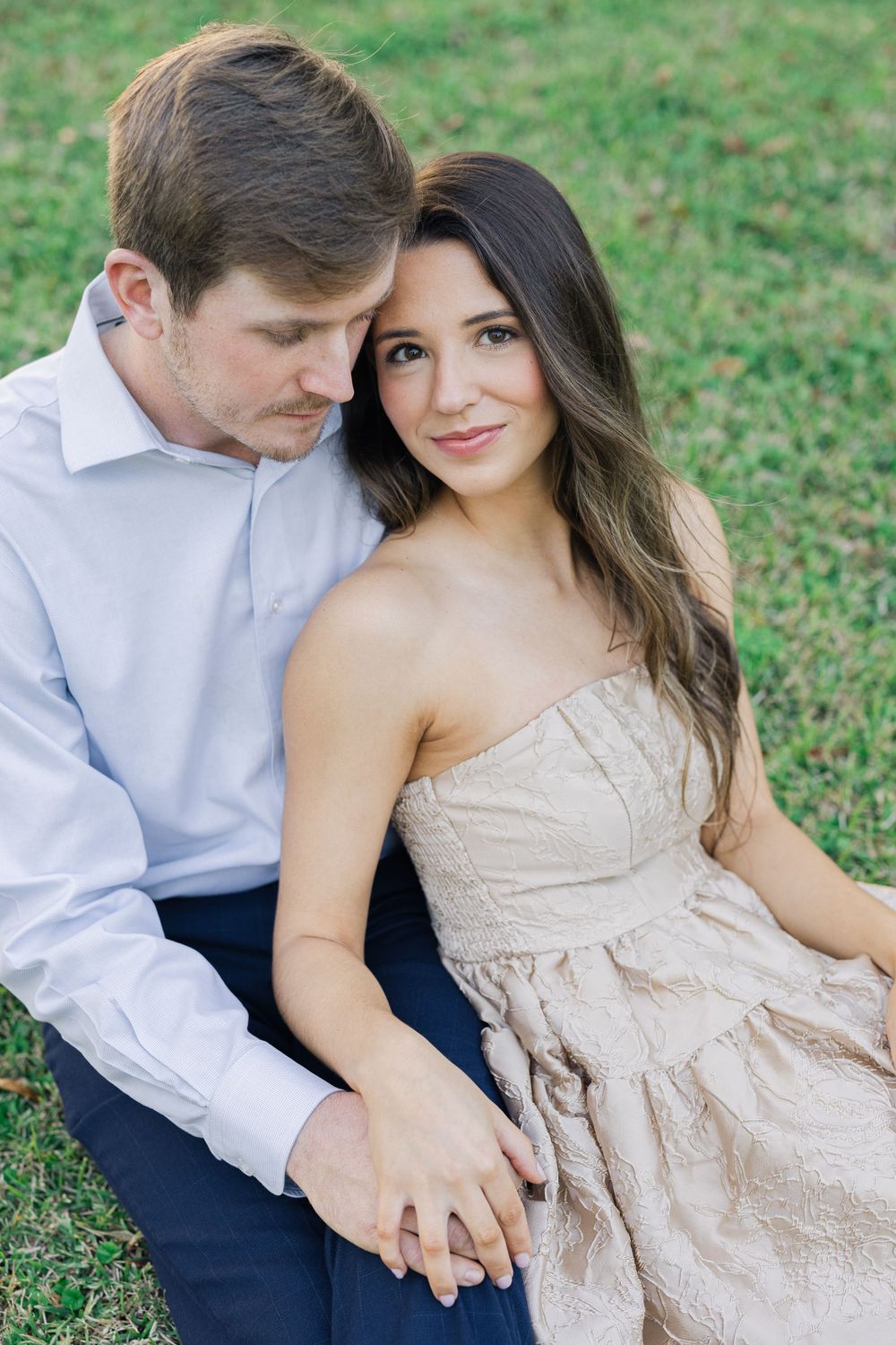 Tender moment between couple sitting together outdoors in formal attire.
