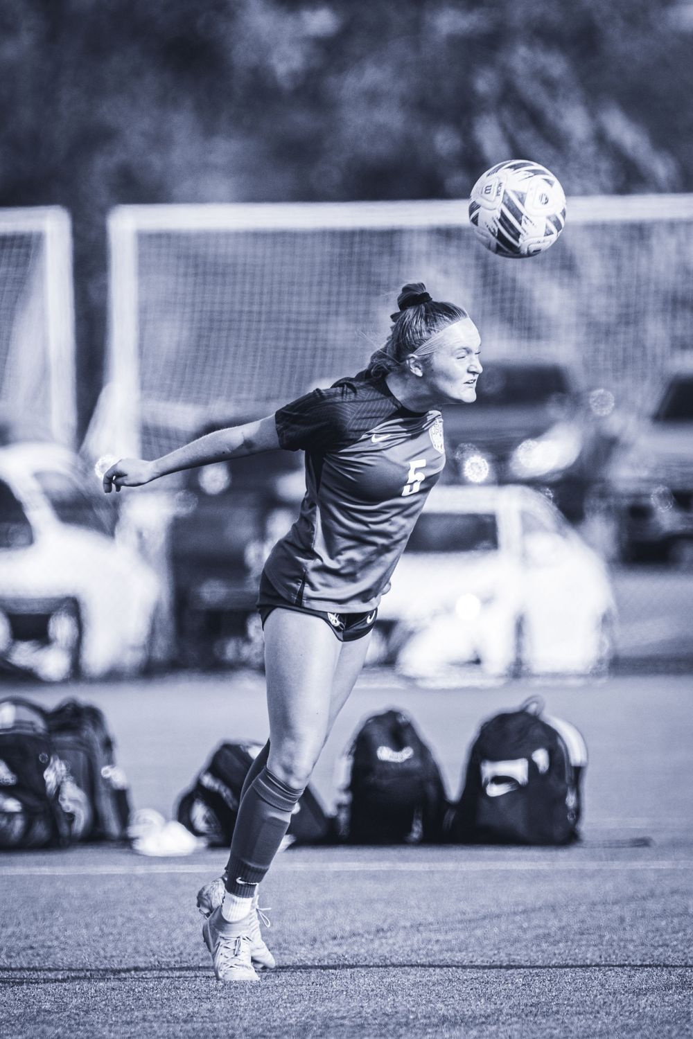 Soccer player performs a jumping header during outdoor game.