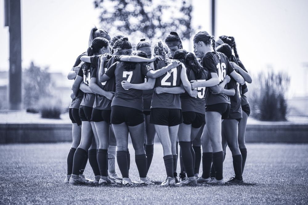 Soccer team huddles together on field before game.