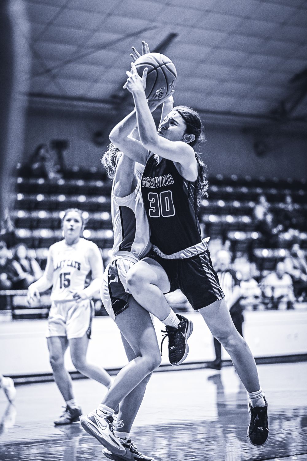 Basketball player wearing number 30 drives to the hoop against a defender during an indoor game.