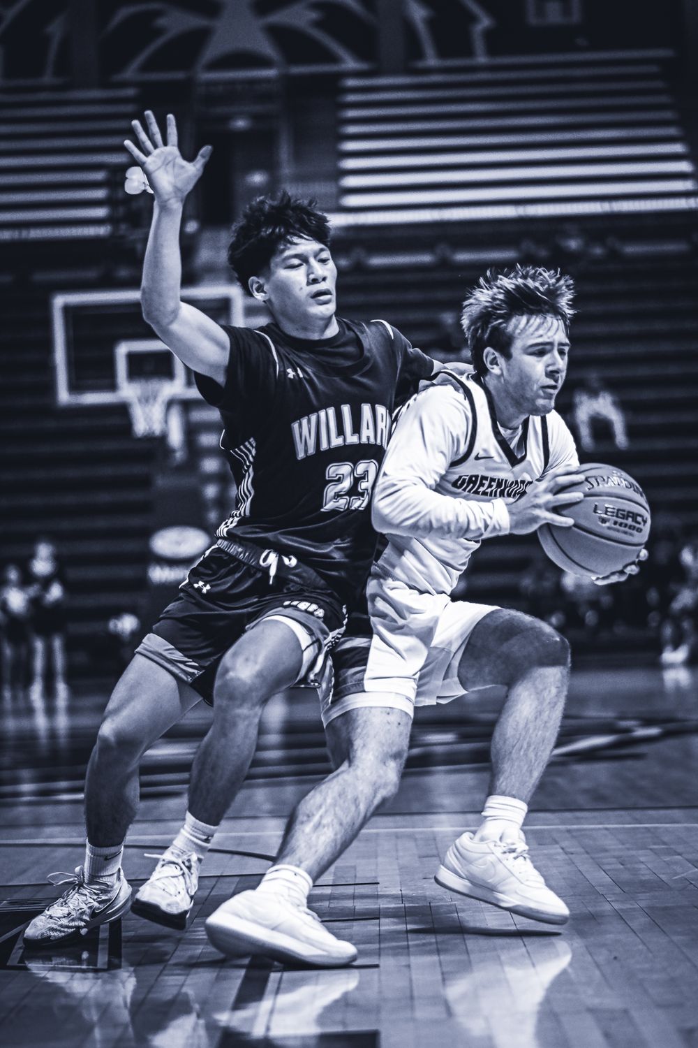 Two basketball players battle for position during intense defensive play.
