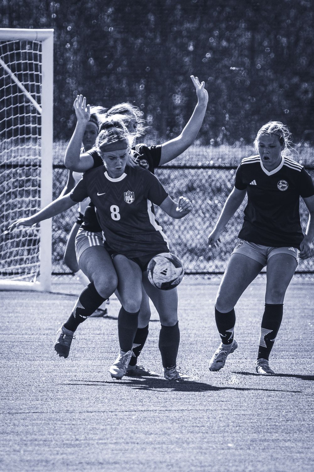 Soccer players compete for ball control near the goal during match.