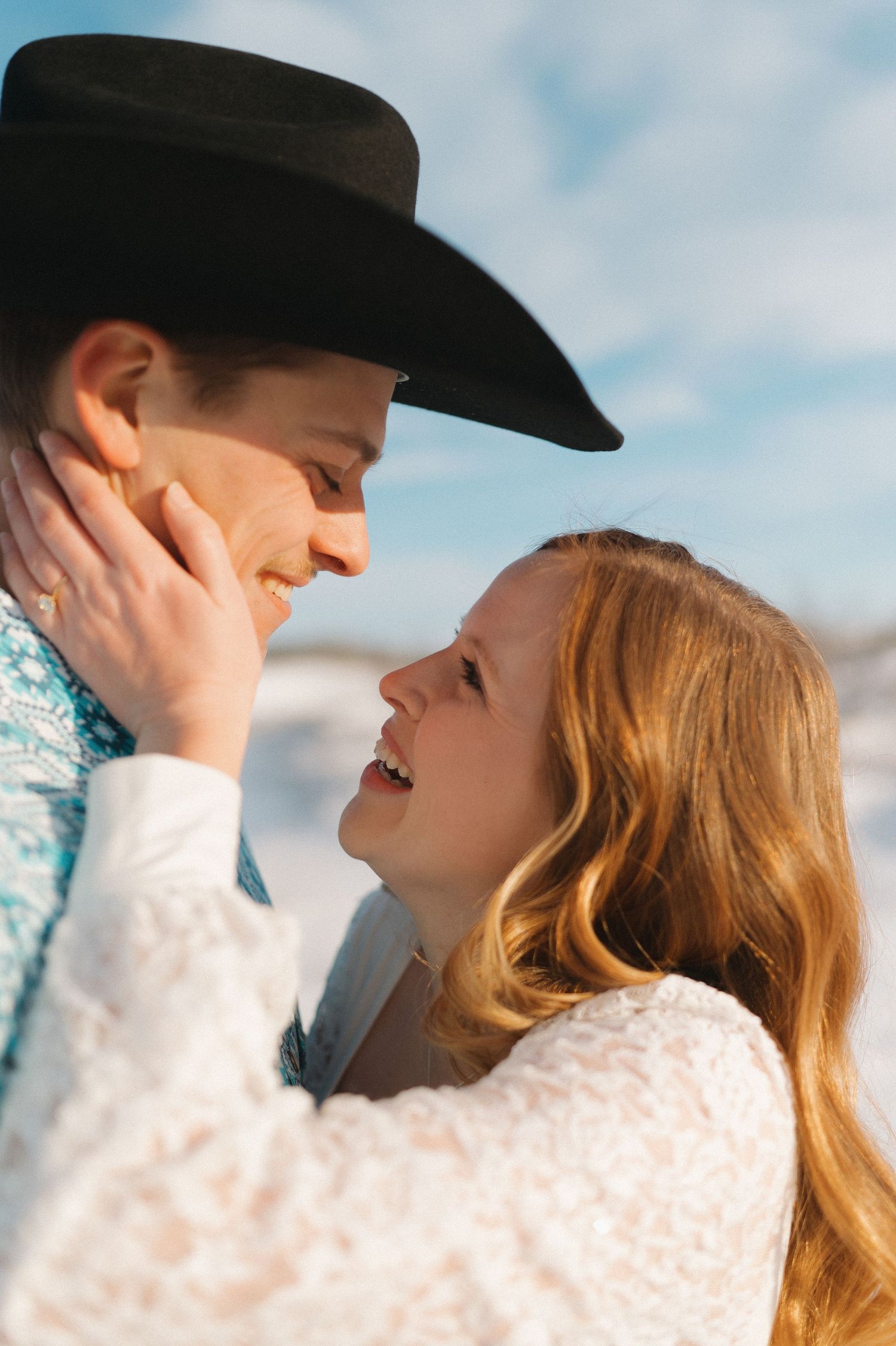 A tender moment between a couple in western-inspired clothing outdoors.