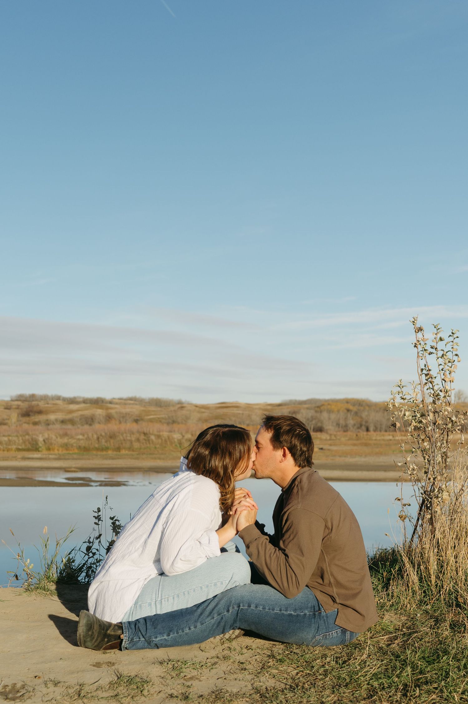 Couple sharing an intimate moment by a lake during golden hour.