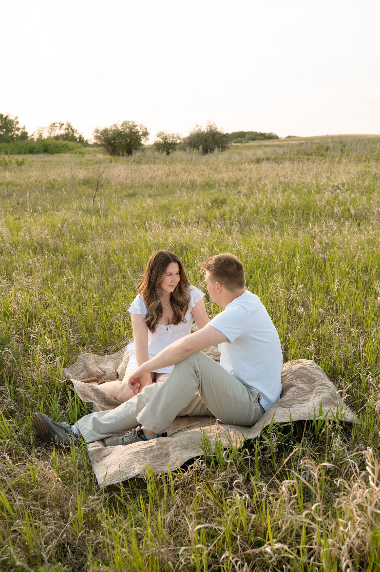 A couple relaxes on a blanket in a sunny wildflower meadow during a romantic summer afternoon.