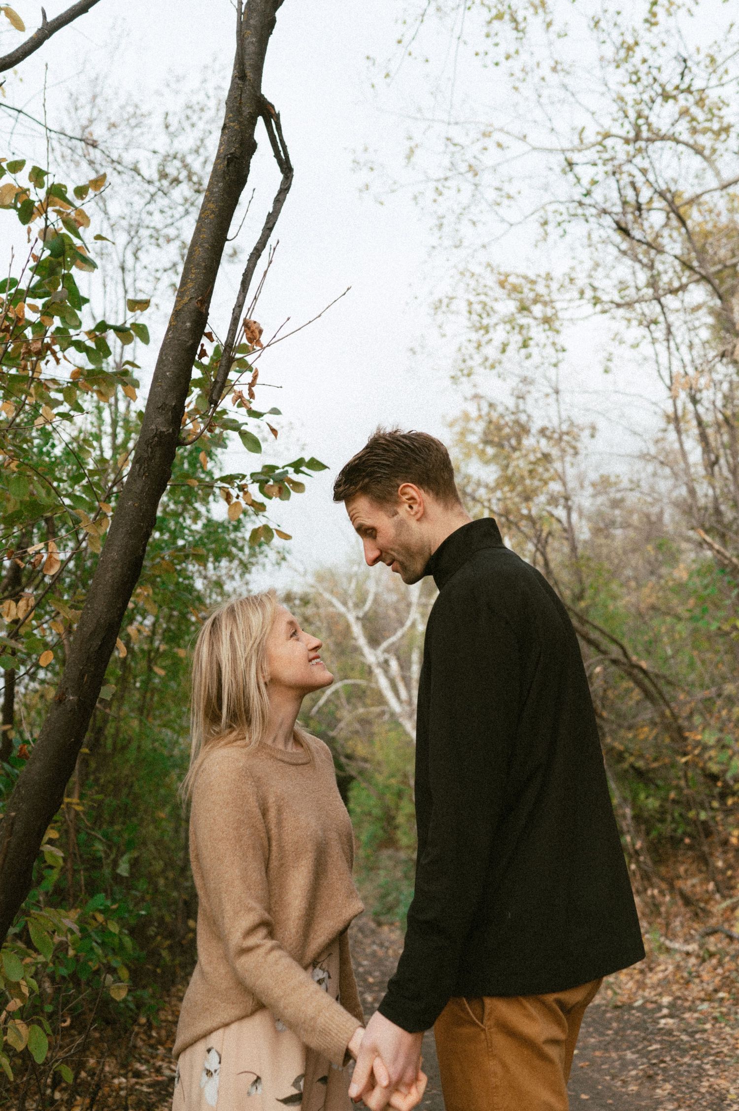 Romantic autumn photo of couple sharing intimate moment on forest path.