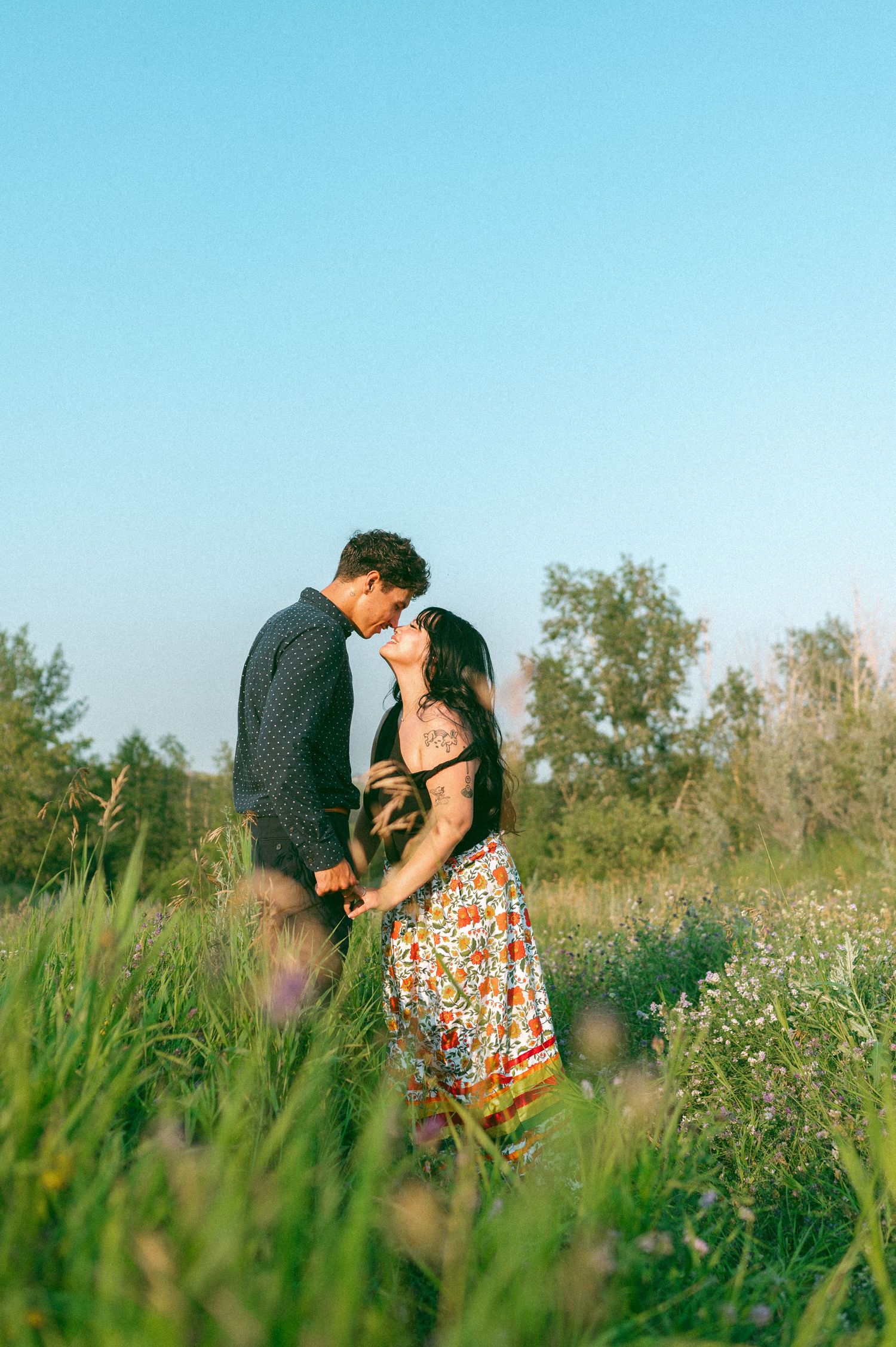 Romantic couple embracing in a wildflower meadow during golden hour.