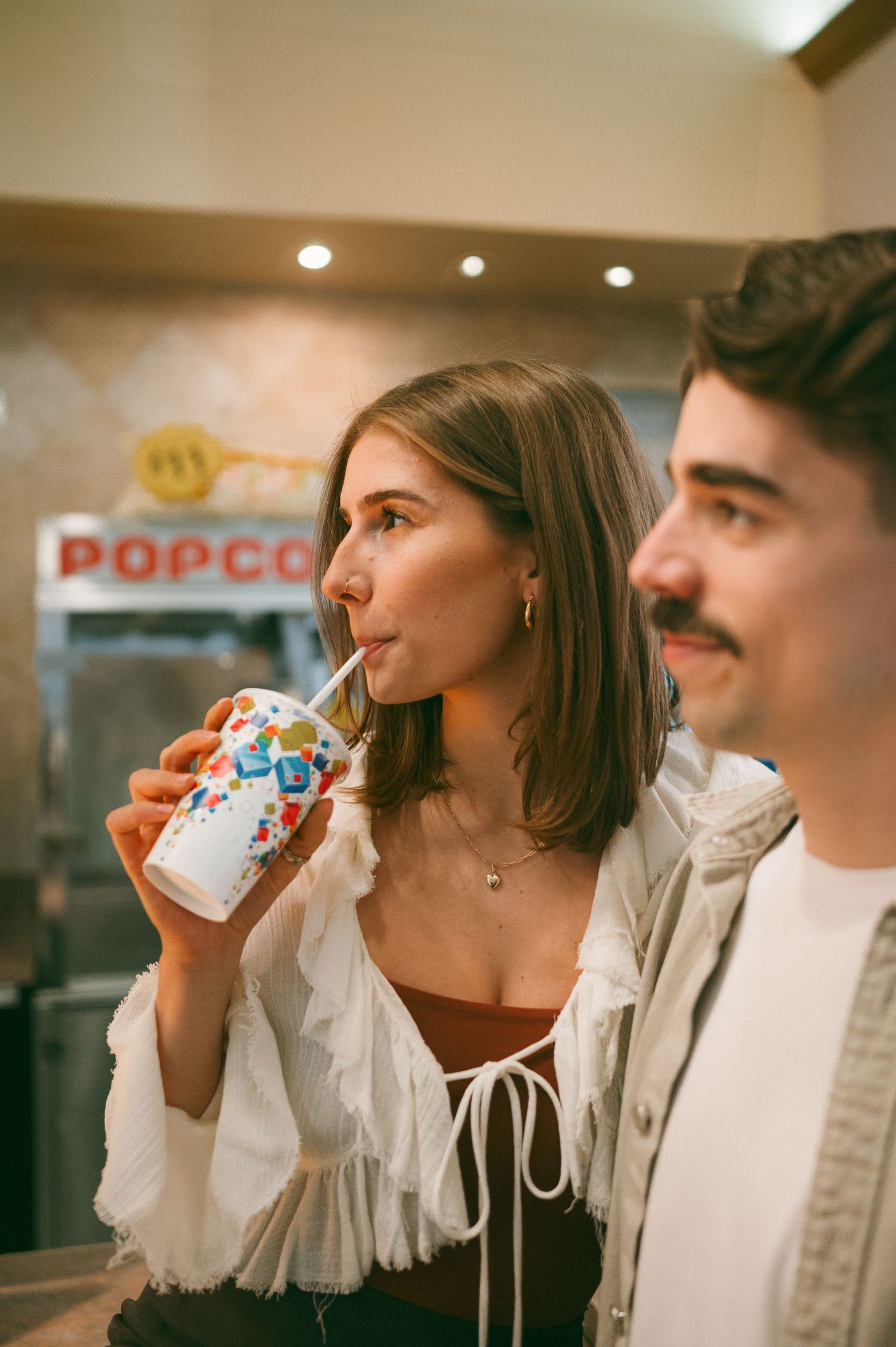 Two people enjoy hot drinks together in a cozy setting shown in a series of connected photographs against warm lighting.