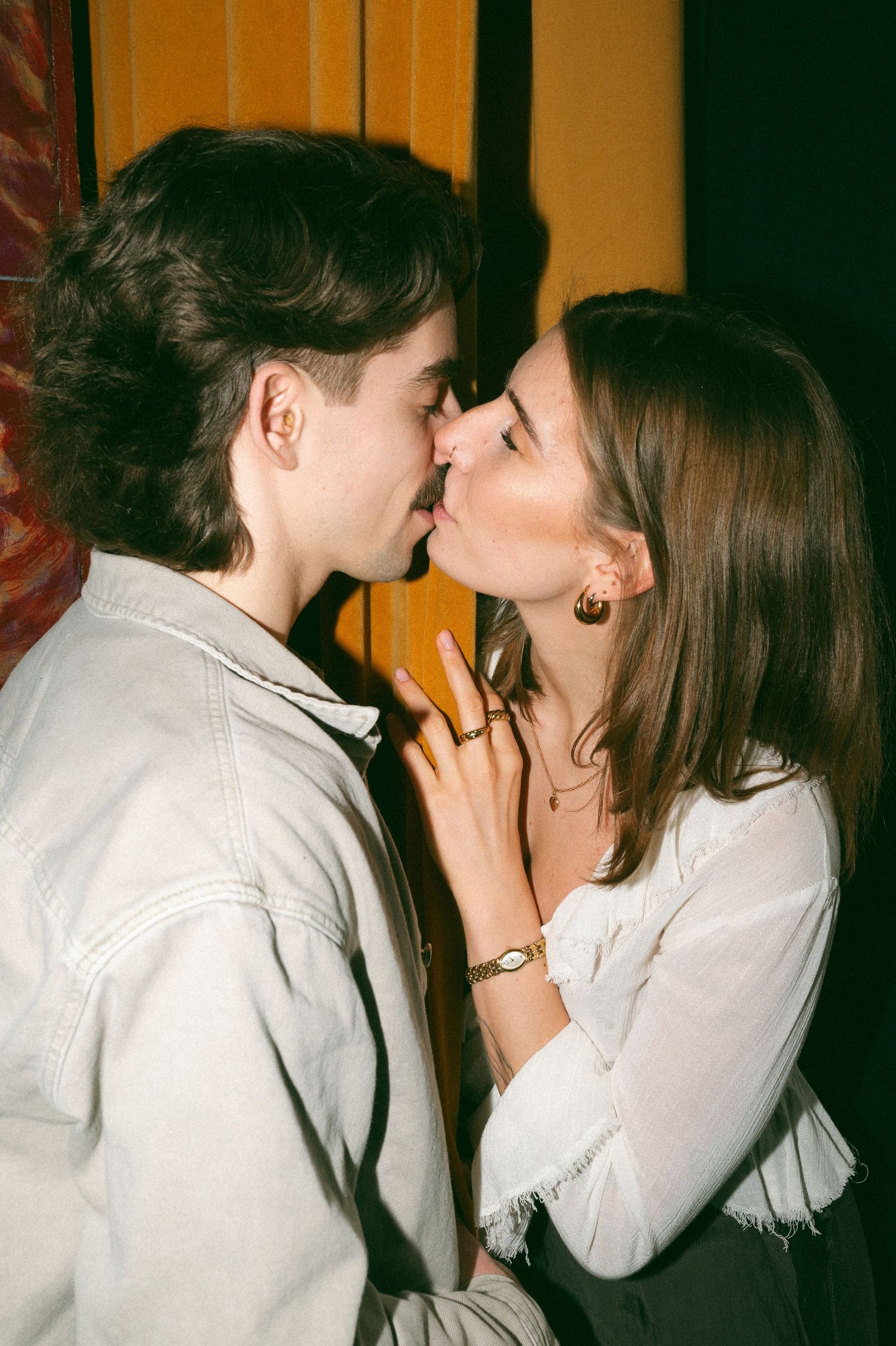Two people sharing an intimate kiss against an orange wall in a film photograph at the Roxy Theatre, Saskatoon Saskatchewan.