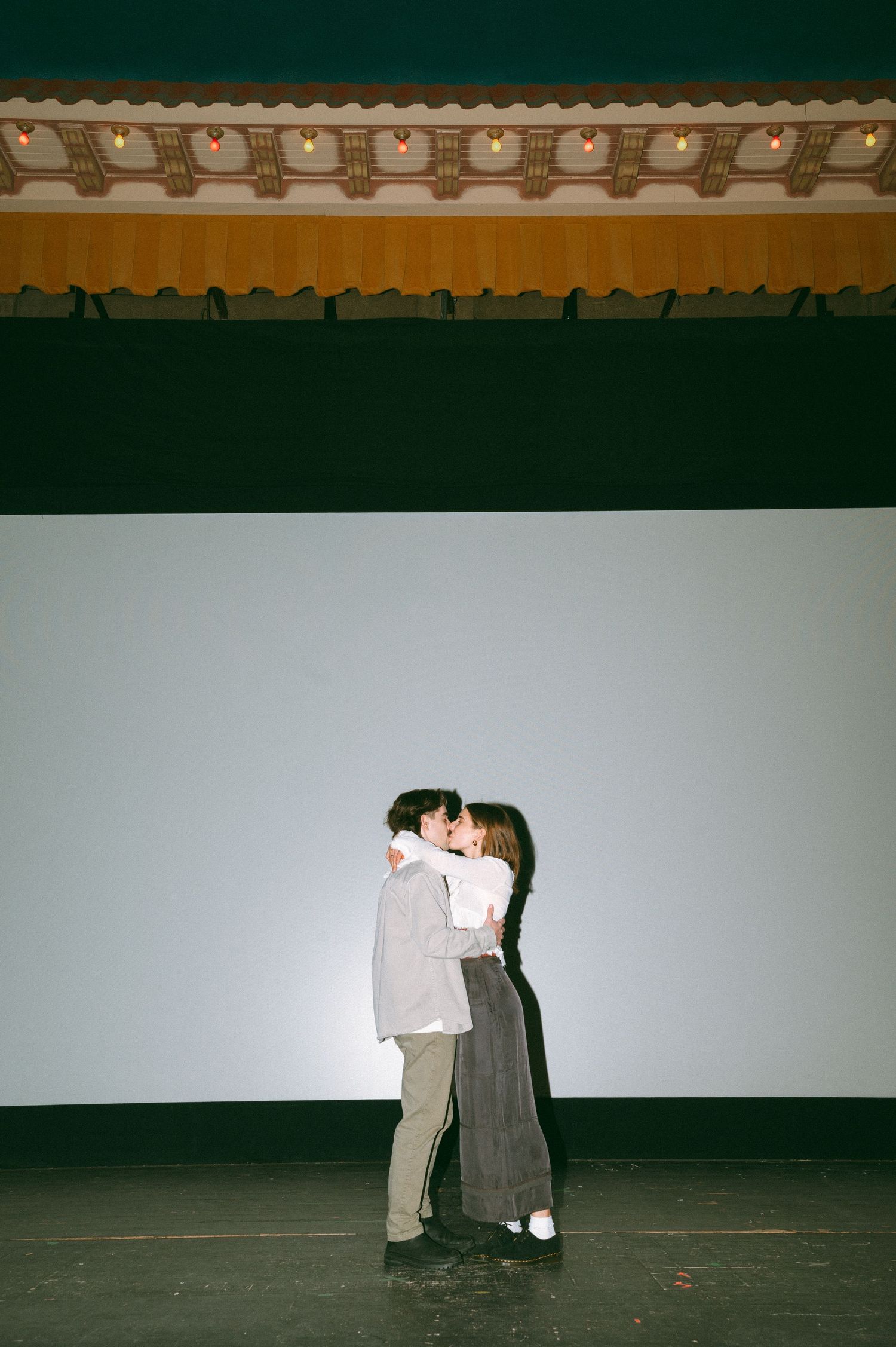 Two figures embrace in silhouette against a plain backdrop under traditional Asian architectural details at the Roxy Theatre, Saskatoon Sask