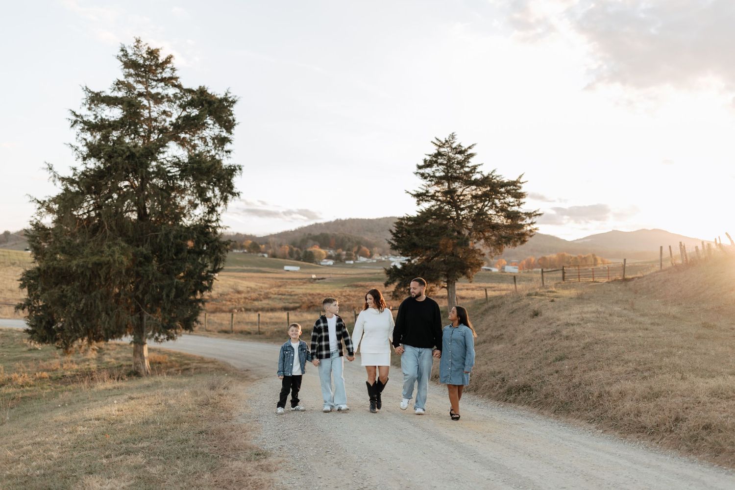 Group walking together on a dirt road through rolling hills at sunset.