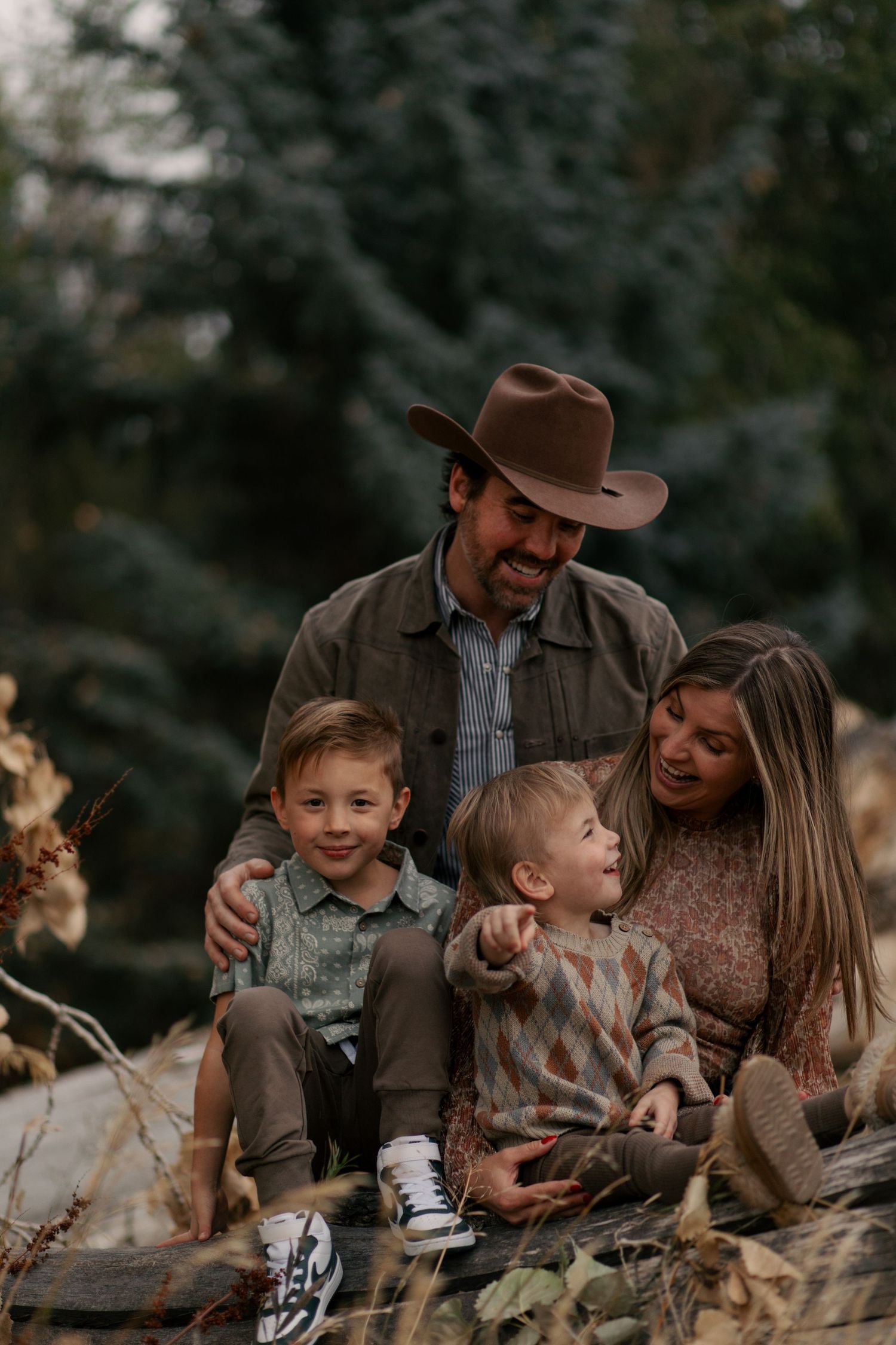 A cozy autumn family portrait outdoors features earthtone clothing and natural scenery in a candid moment together.