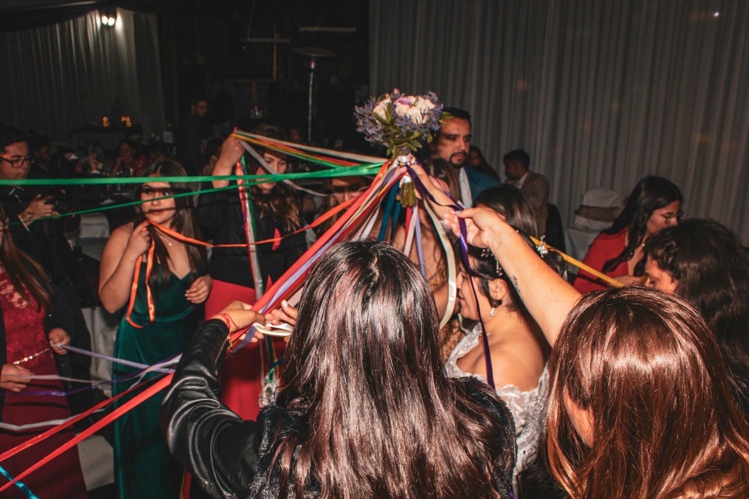 Party crowd dances and celebrates with red and green ribbons at a nightclub event.
