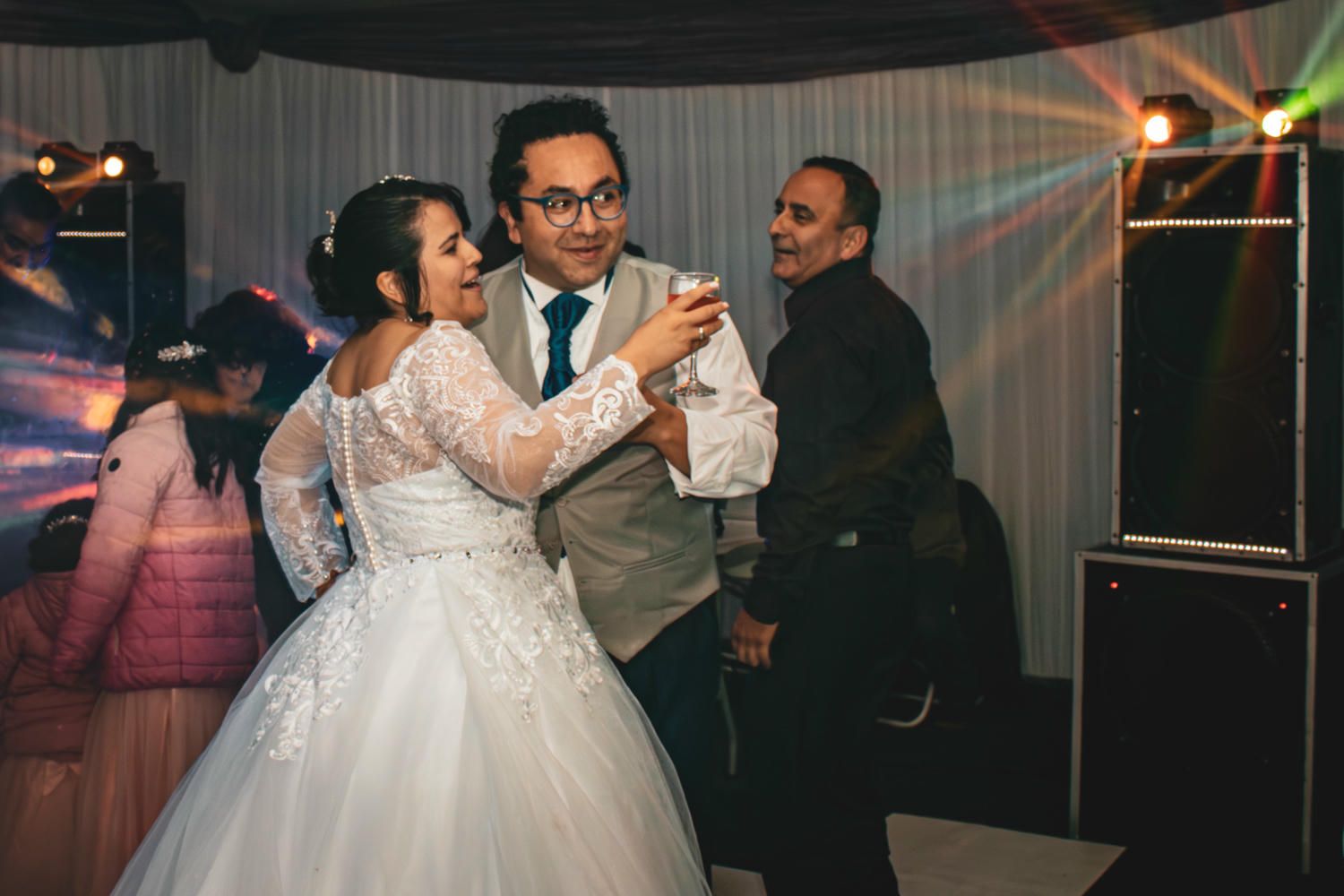 A couple shares their first dance at a wedding reception while guests watch from the sides of the dance floor.