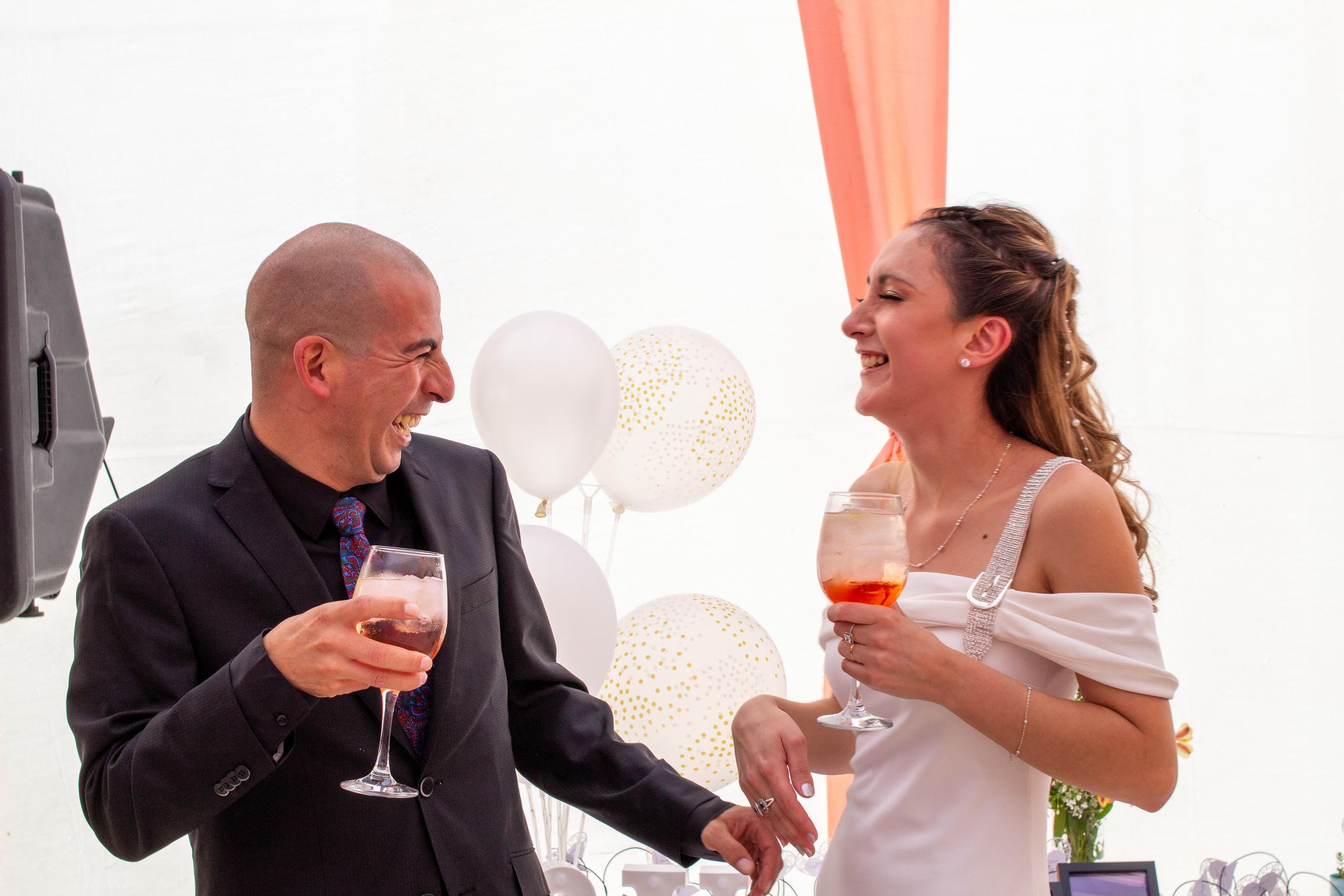 Pareja de novios brindando con copas de champaña al aire libre con luz natural.