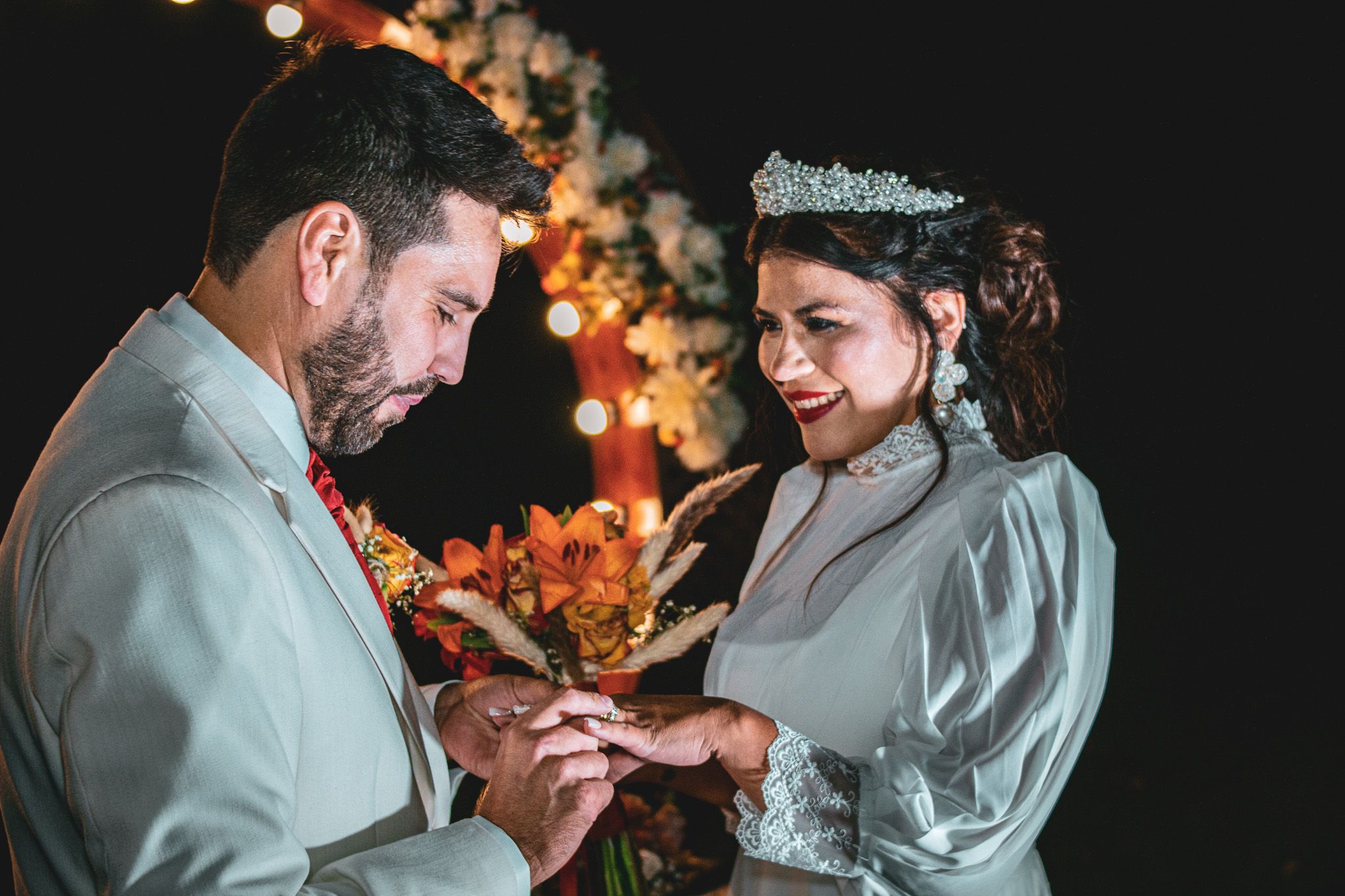 Pareja compartiendo momento íntimo durante celebración de matrimonio con luz cálida y bokeh.