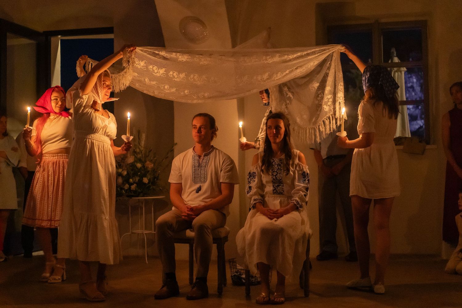 A traditional Slovakian čepčenie ceremony - maidens in white encircle the bride and groom, holding candles and a lace sheet above them