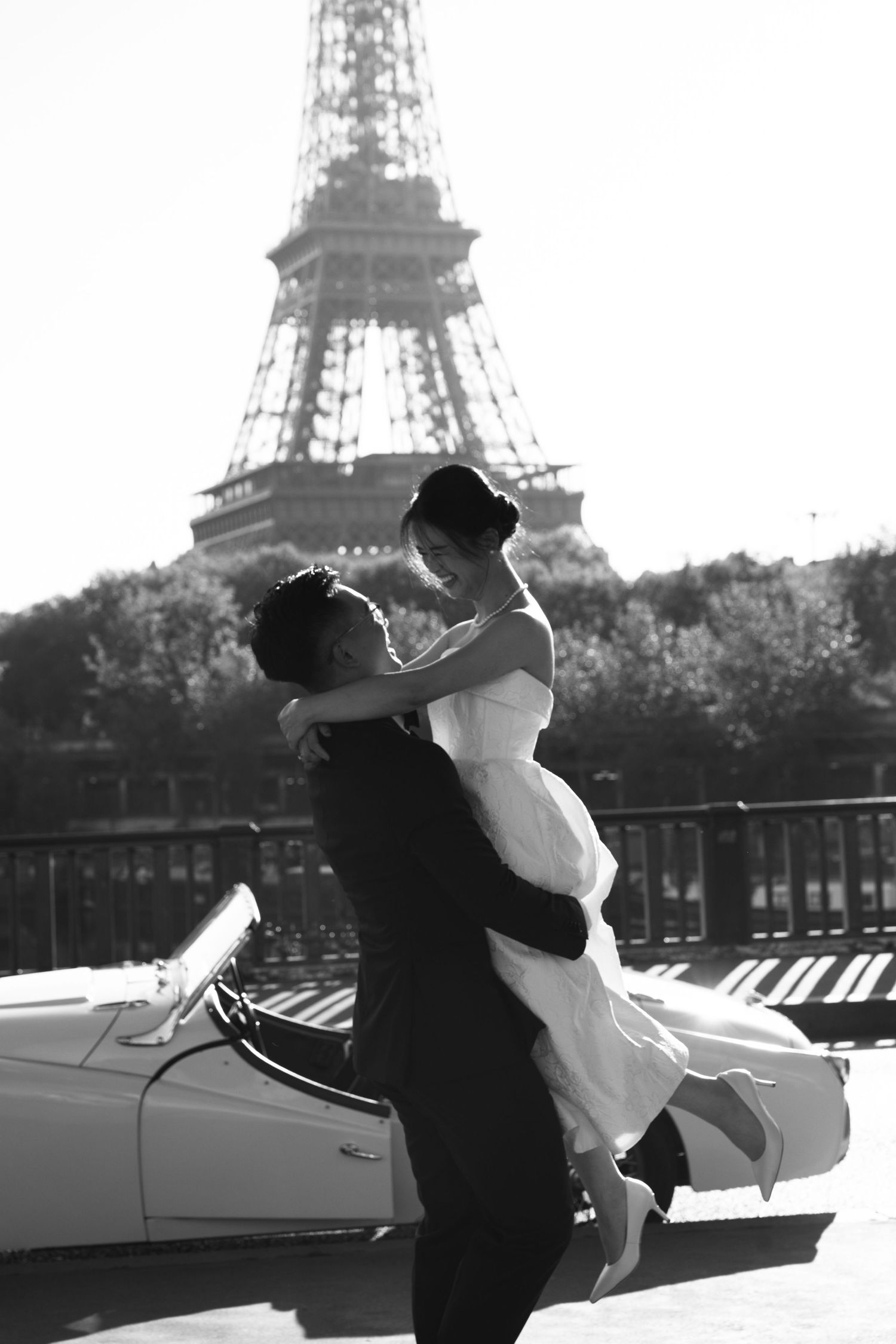 A couple dancing together under elegant stone archways with palm trees visible in the background.