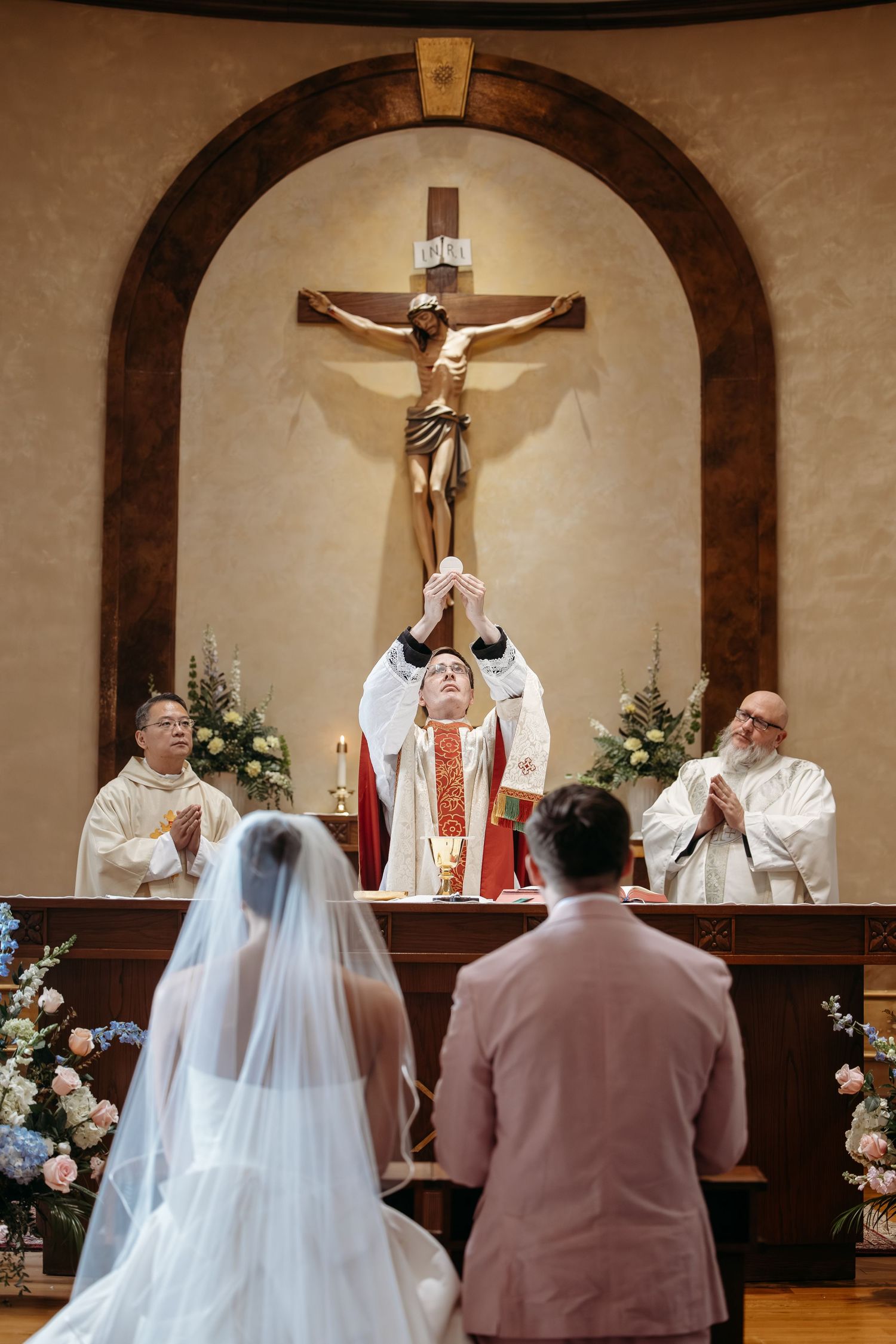 The Eucharistic Consecration during a St. Louis Catholic wedding Mass takes place at the altar of Ascension Catholic Church under a crucifix