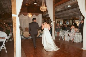 Wedding reception dance floor in a barn with twinkle lights and white fabric draping creating an elegant atmosphere.