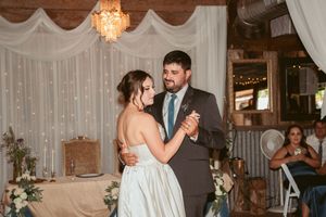 Romantic dance in rustic barn venue with fairy light backdrop and elegant crystal chandelier overhead.