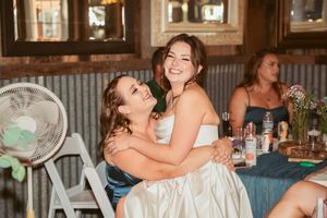 Wedding guests laugh and dance together during a lively celebration at a rustic barn reception venue.