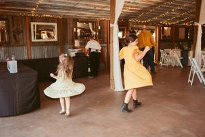 Rustic barn wedding reception venue with exposed wooden beams, string lights, and white fabric draped decorations.