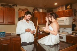 Two people in a kitchen engaged in a playful flour battle while baking, creating a mess of white powder in the air.