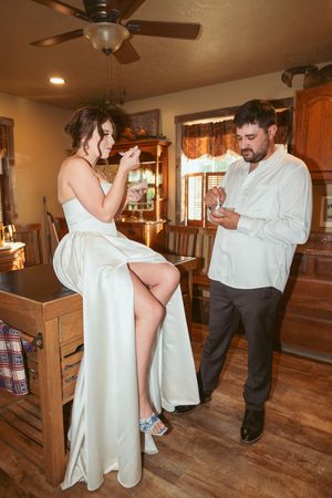 A couple enjoying a playful moment in a kitchen setting, with a person in a white dress seated on a counter.