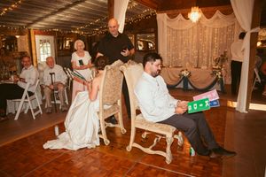 People dance across a rustic wooden dance floor at a barn wedding reception with string lights overhead.