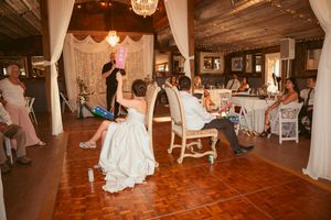 Wedding reception game in a rustic barn venue with white draped decor and chandelier lighting.