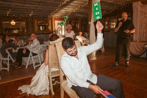 Wedding guests dance on a rustic wooden dance floor under twinkling lights during the celebration.