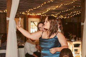 Party guests dance and celebrate beneath string lights at an indoor reception venue.
