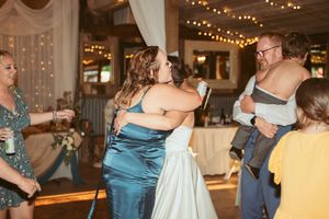 Wedding party dancing together in a warmly lit reception venue with string lights and decorative draping.