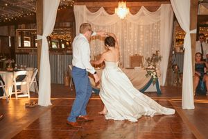 Dancing couples share romantic moments during a wedding reception in a rustic barn setting with twinkle lights.