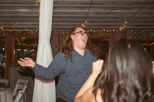 Guest dancing enthusiastically at indoor reception with string lights in background.