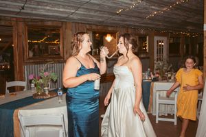 Wedding guests share a joyful moment at an indoor reception with string lights and rustic decor.