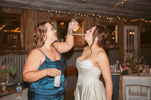 Wedding guests dance and celebrate on an illuminated dance floor at an indoor reception venue.