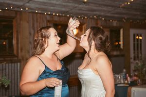 Wedding celebration dancing in a barn-style venue with string lights and white draping.