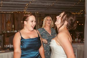 Candid moment of celebration and laughter at a wedding reception under strings of glowing lights.