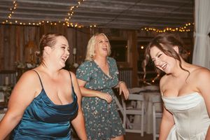 Wedding party guests dancing and celebrating on wooden dance floor under string lights.