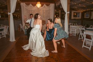 Celebration in full swing at rustic wedding venue with elegant white drapes and chandeliers.