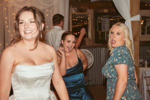 Wedding party enjoying dance floor moments under rustic barn lighting.