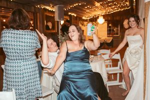 Wedding guests dancing and celebrating in a venue decorated with string lights and white chairs.